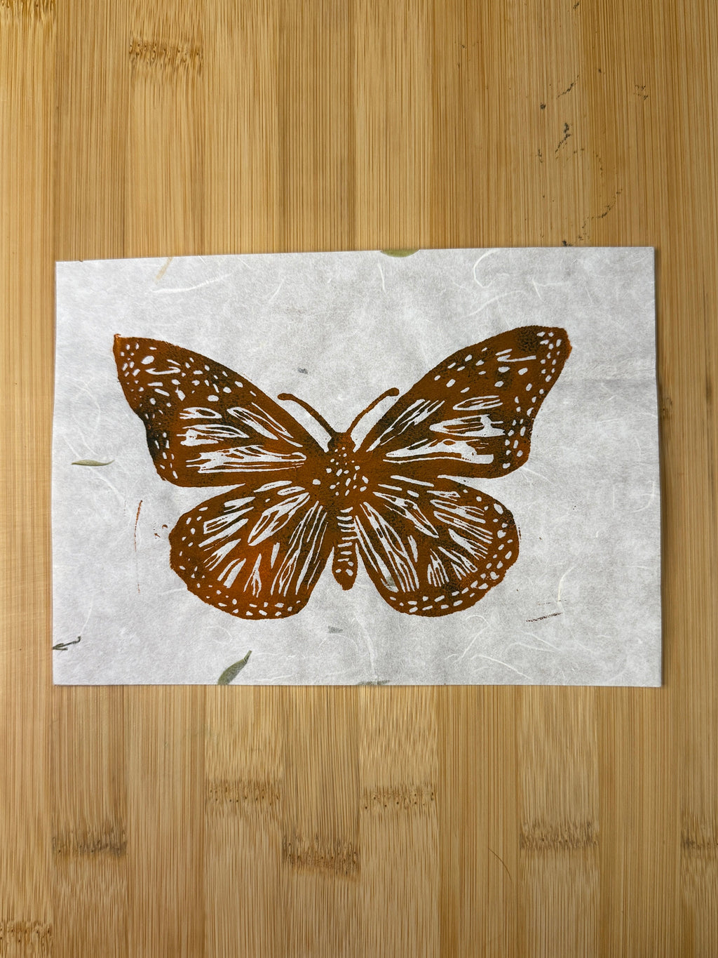 Brown butterfly design on a white paper sheet placed on a wooden surface