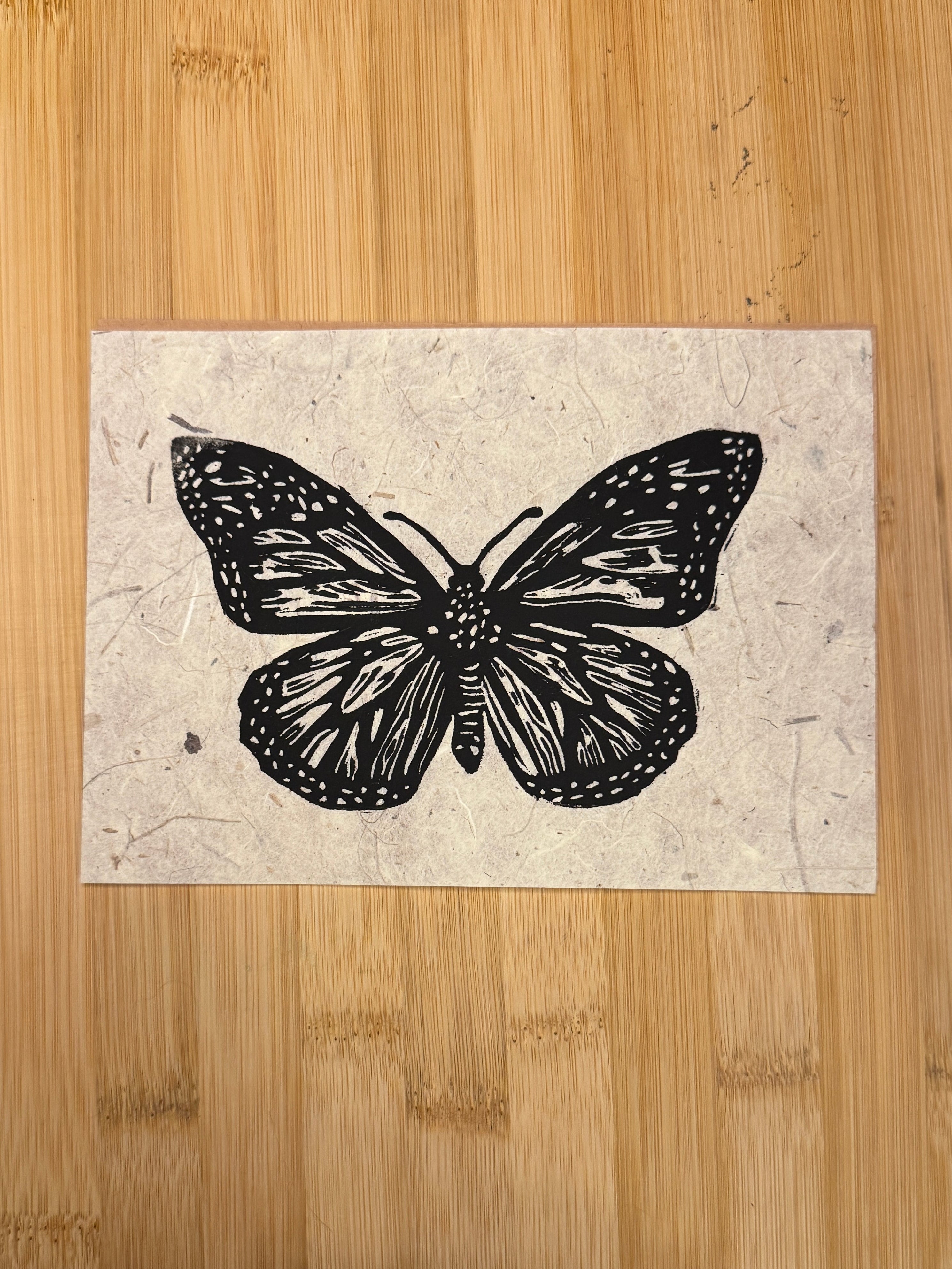 Butterfly illustration on a textured paper placed on a wooden surface.