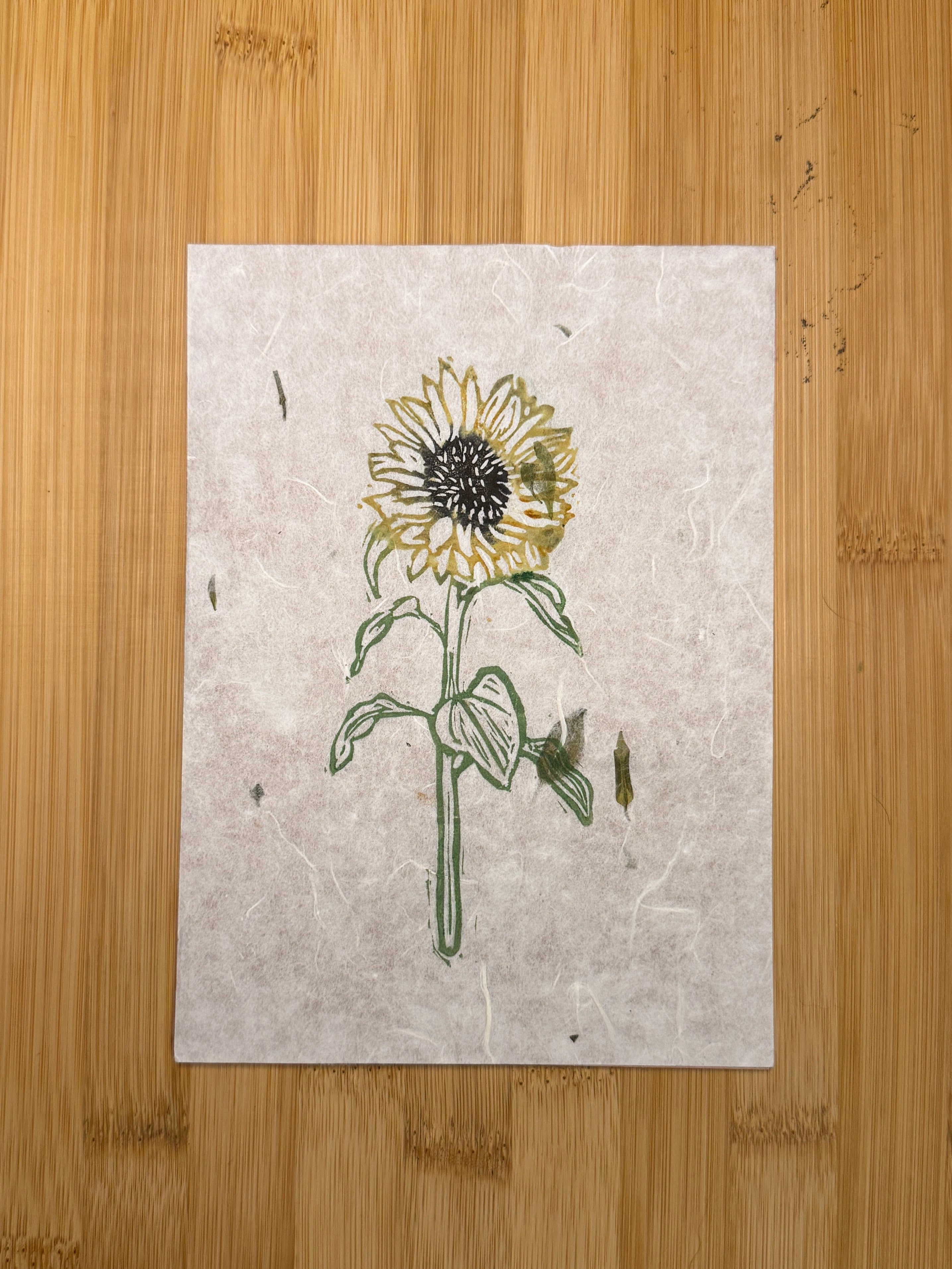 Yellow and green floral print on a piece of paper placed on a wooden surface.