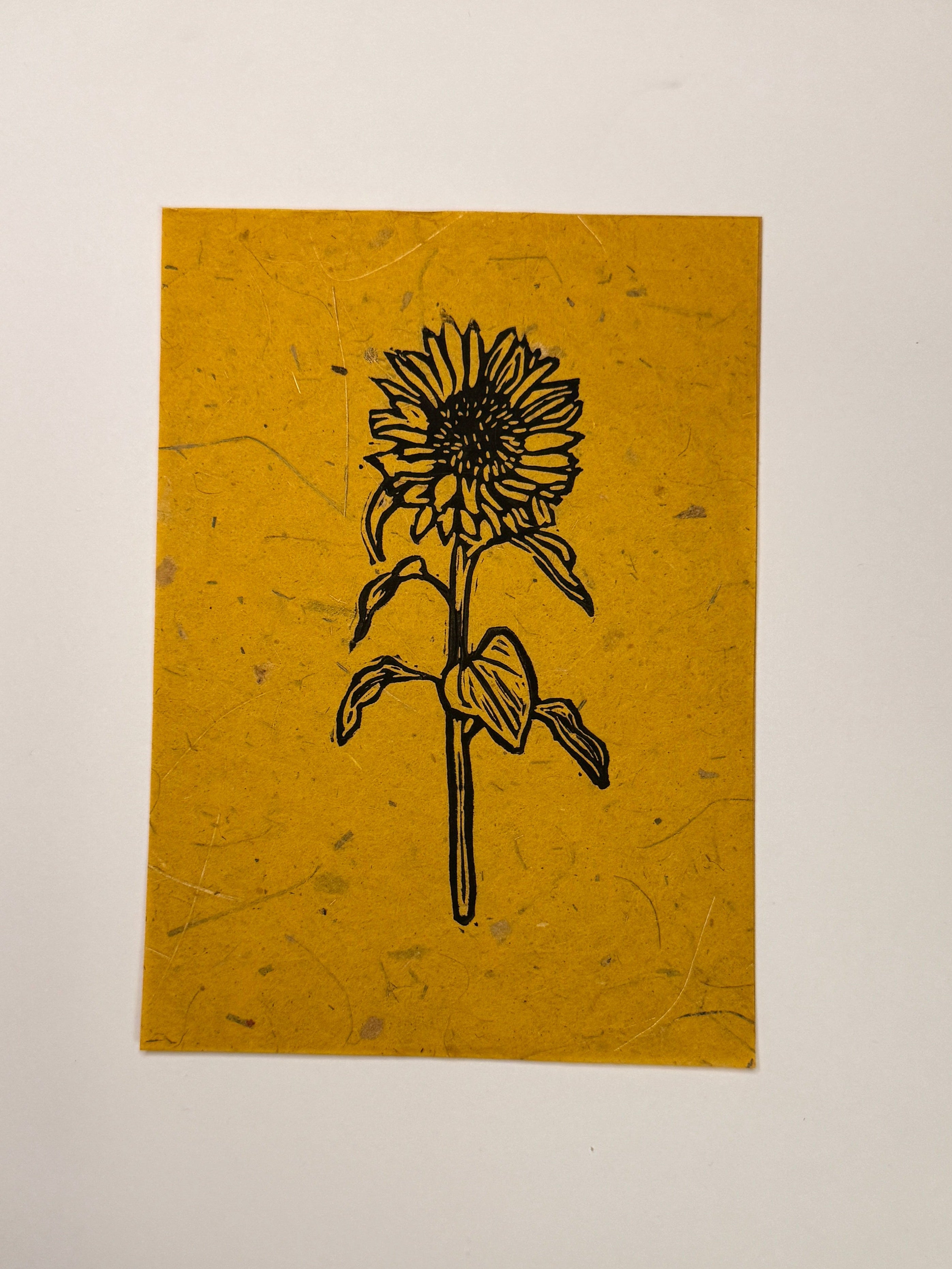 Print of a flower on yellow paper, placed on a wooden surface.