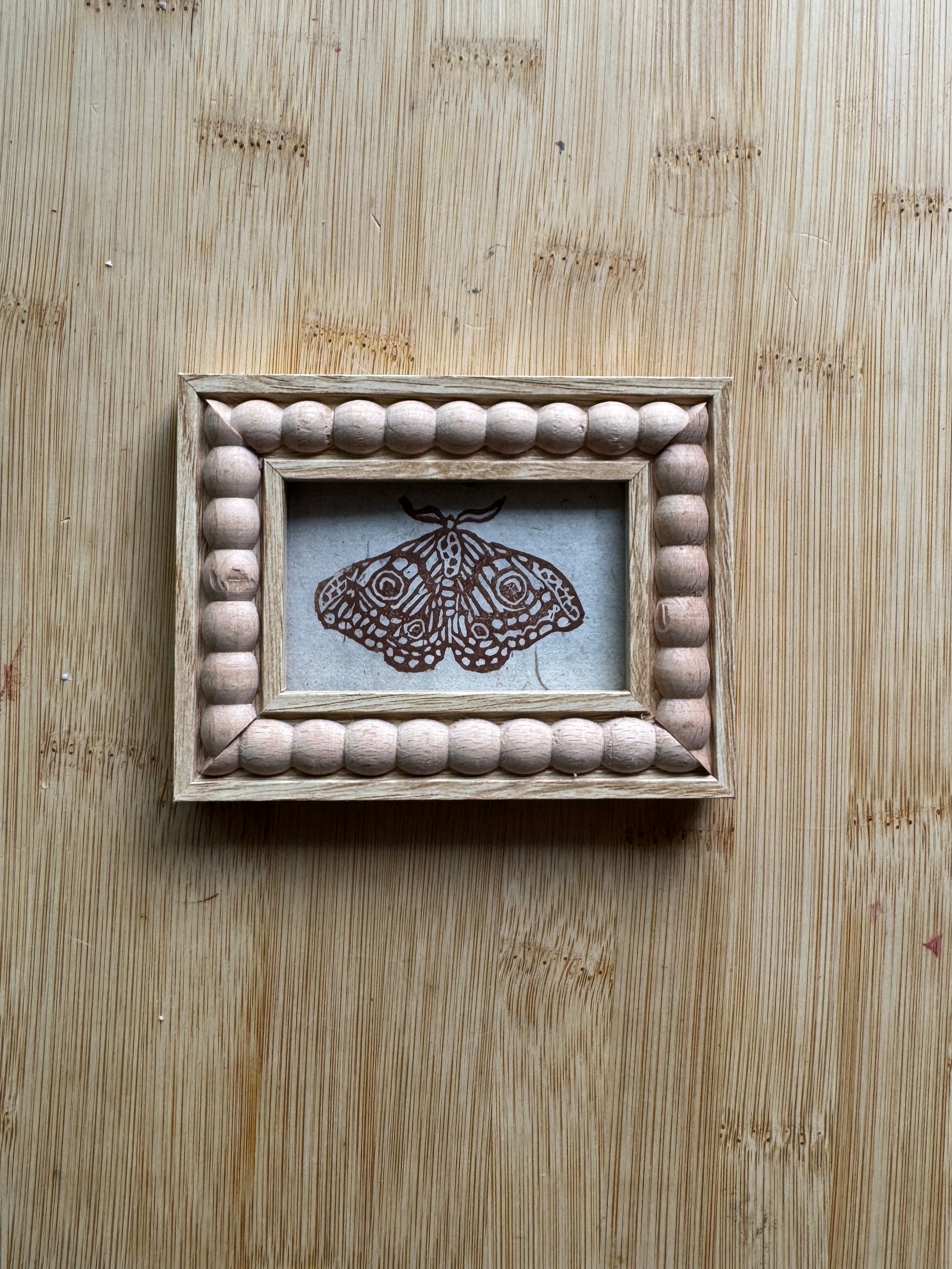 Wooden frame with a moth design on a wooden surface